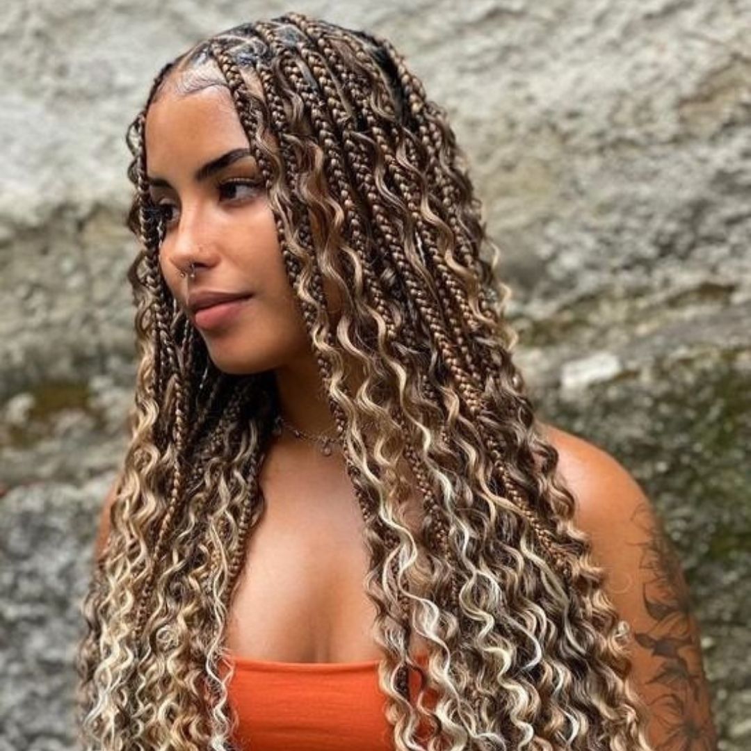 Mujer con trenzas bohemias (goddess) en tonos miel y rizos sueltos