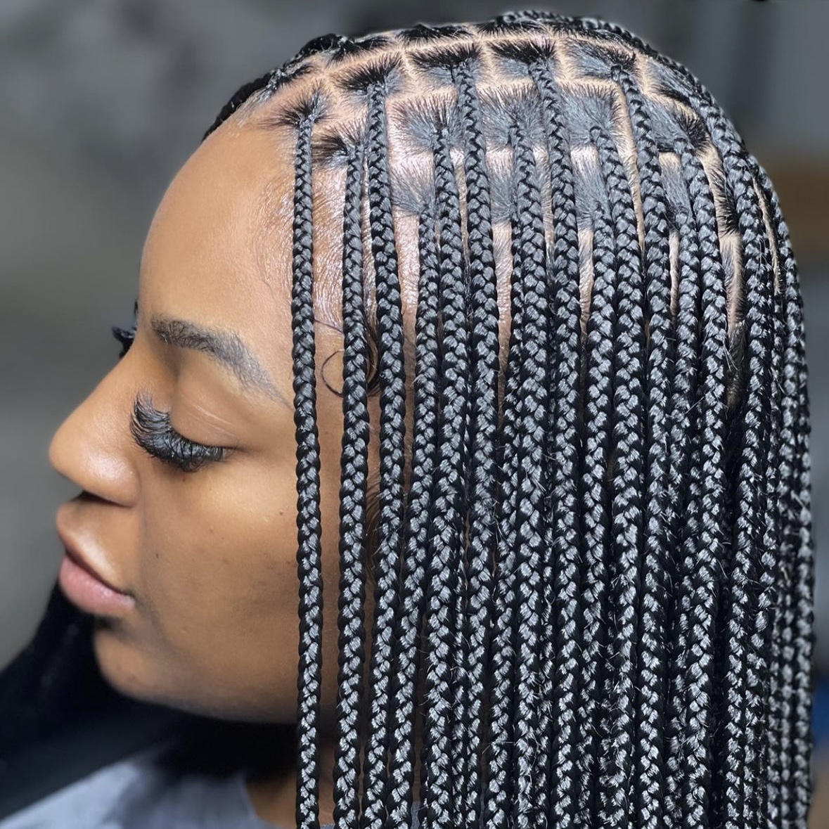 Perfil de mujer con knotless braids negras y secciones cuadradas definidas